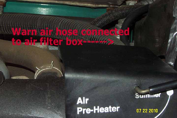 Shows the warm air supply hose connected to the round hole on the rear of the plastic air filter box.